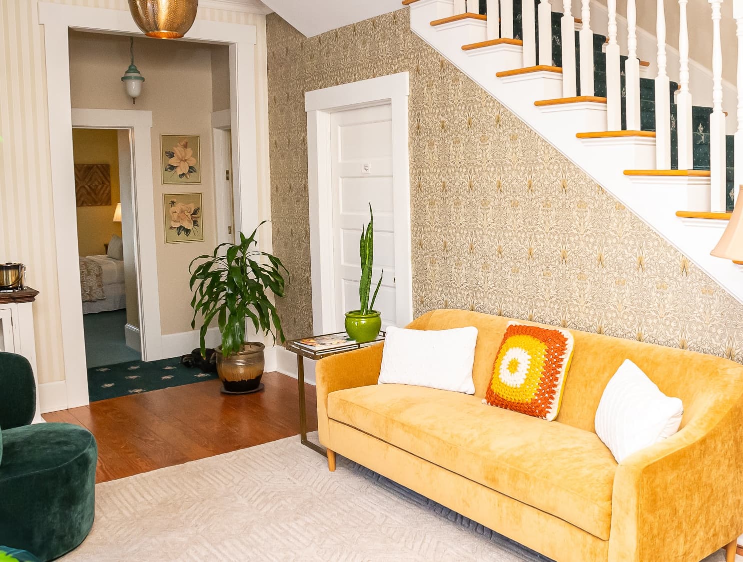Cozy living space featuring a yellow couch, green plant, and stylish wallpaper.