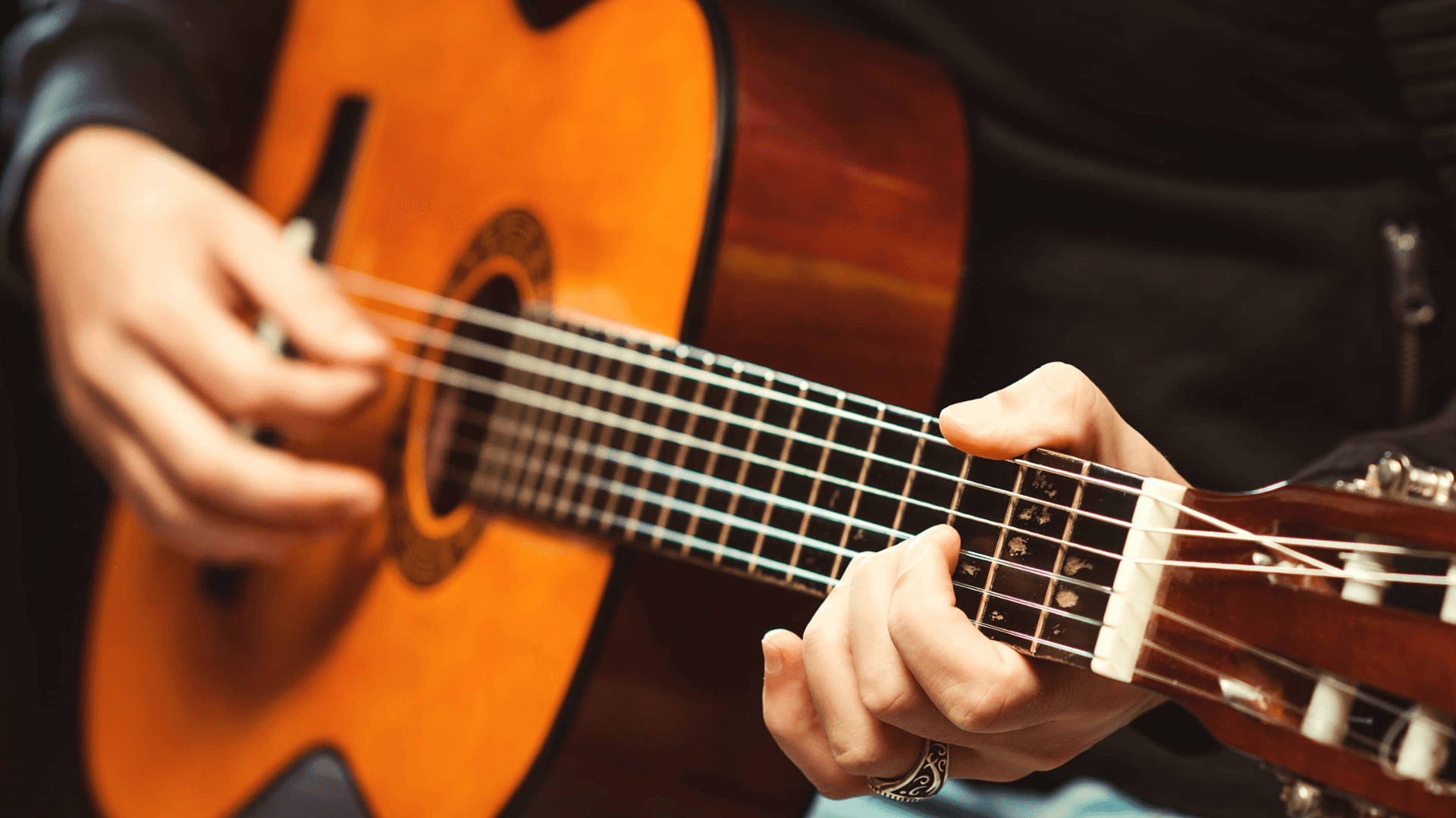 A person strums an acoustic guitar.